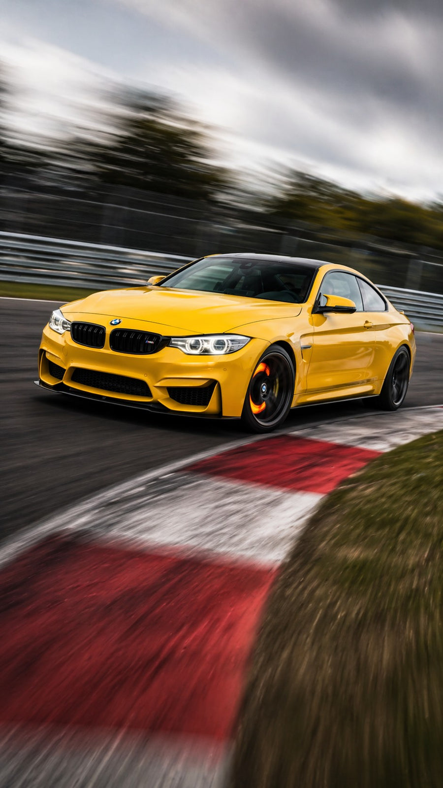 Yellow BMW M4 on track showing red hot brake rotor heat